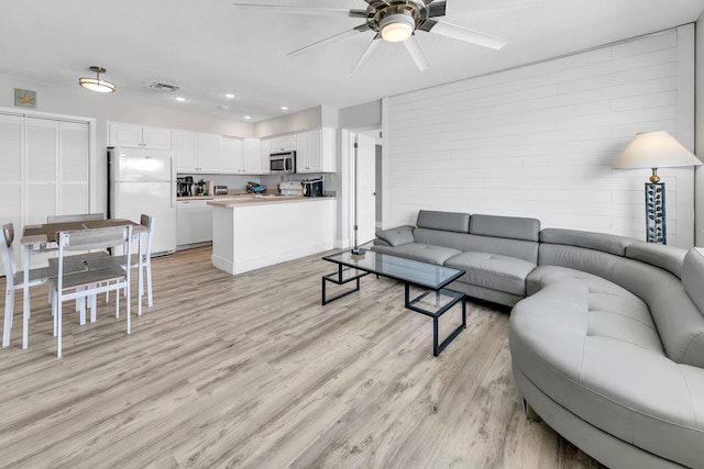 living area with light wood finished floors, visible vents, ceiling fan, wood walls, and recessed lighting