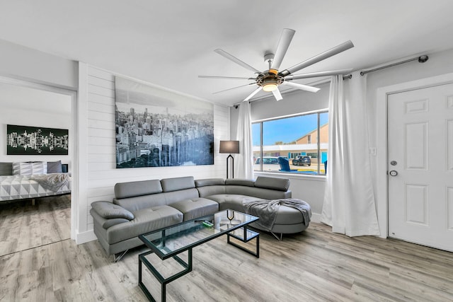 living room featuring baseboards, a ceiling fan, and wood finished floors