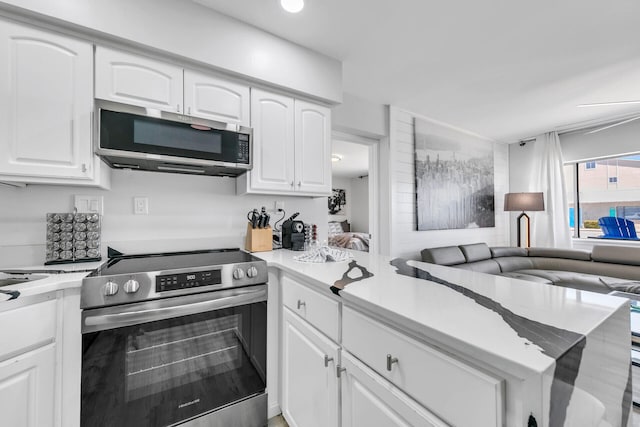 kitchen with white cabinets, open floor plan, light countertops, and appliances with stainless steel finishes