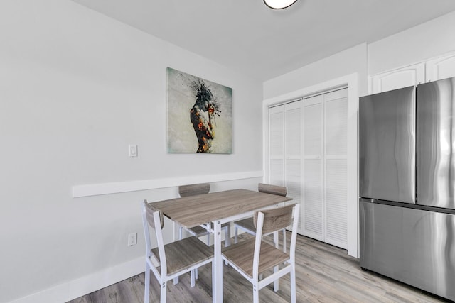 dining space featuring baseboards and light wood-type flooring