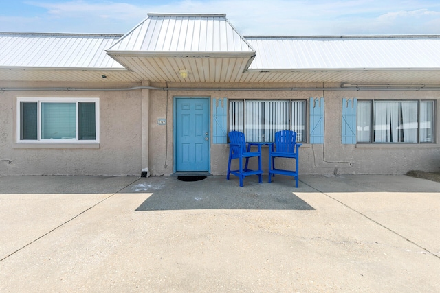 view of exterior entry featuring a patio and stucco siding