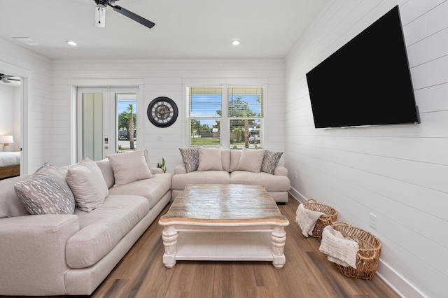 living room featuring ceiling fan, wood-type flooring, and wood walls