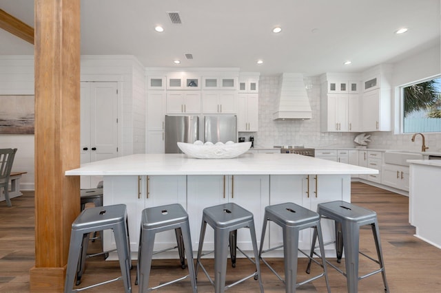 kitchen with sink, a spacious island, premium range hood, and appliances with stainless steel finishes