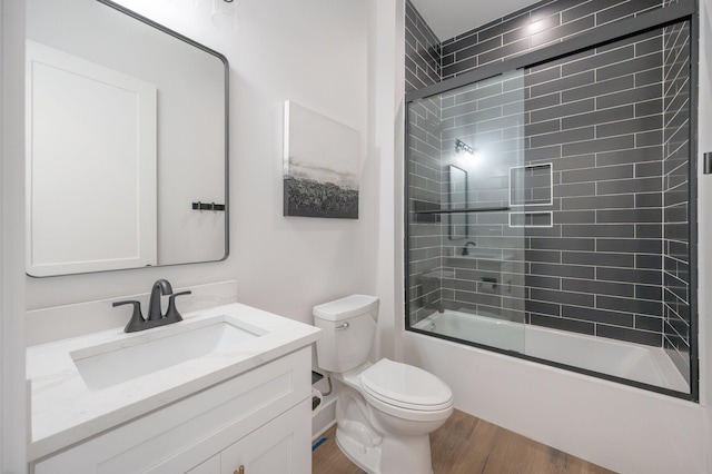 full bathroom featuring wood-type flooring, vanity, toilet, and bath / shower combo with glass door