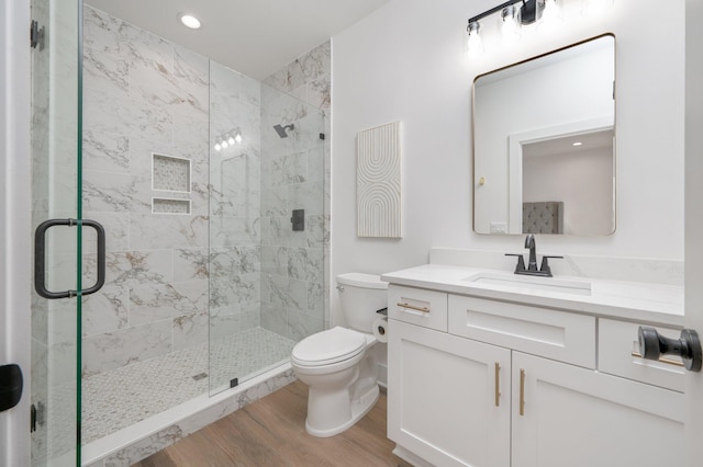 bathroom with hardwood / wood-style flooring, vanity, toilet, and a shower with shower door