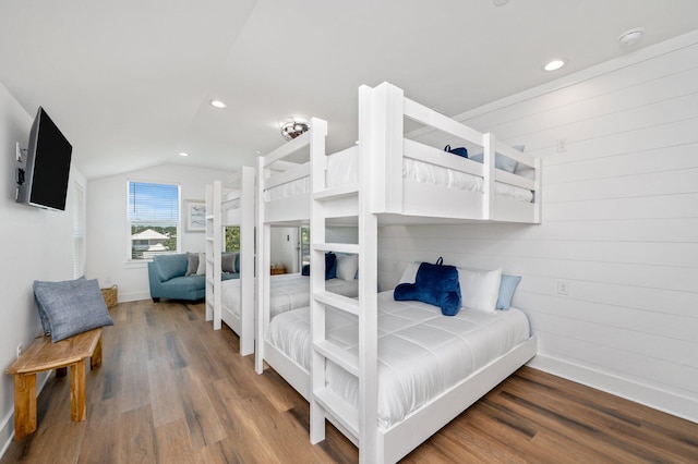 bedroom with wooden walls, wood-type flooring, and vaulted ceiling