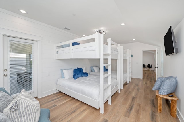 bedroom with wood-type flooring, lofted ceiling, and wooden walls