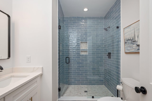 bathroom featuring a shower with door, vanity, and toilet