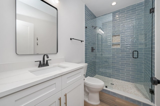 bathroom featuring hardwood / wood-style floors, vanity, toilet, and a shower with shower door