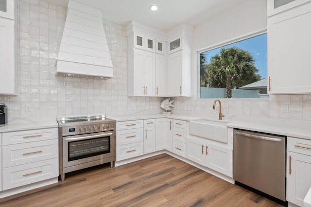 kitchen featuring white cabinets, appliances with stainless steel finishes, backsplash, and premium range hood