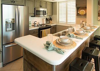 kitchen featuring stainless steel appliances, gray cabinets, kitchen peninsula, backsplash, and light tile flooring