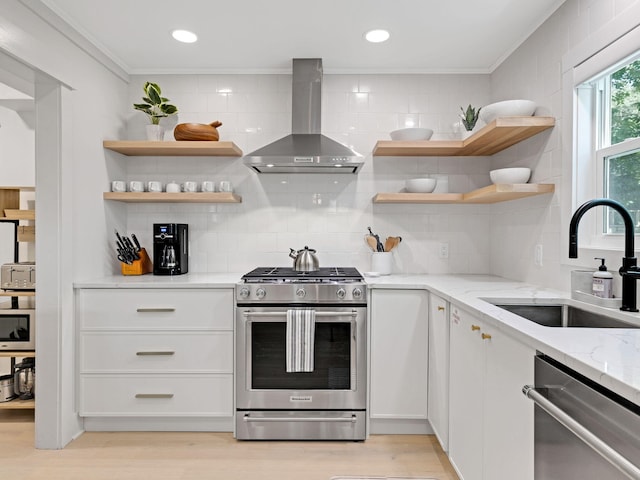 kitchen with white cabinetry, sink, wall chimney exhaust hood, light stone counters, and appliances with stainless steel finishes