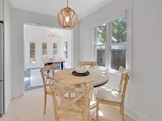 dining area featuring light hardwood / wood-style flooring, a notable chandelier, and crown molding