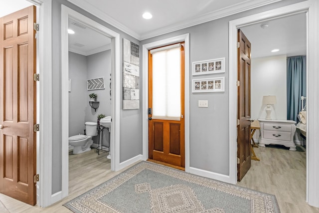 interior space with ornamental molding, wood-type flooring, and toilet