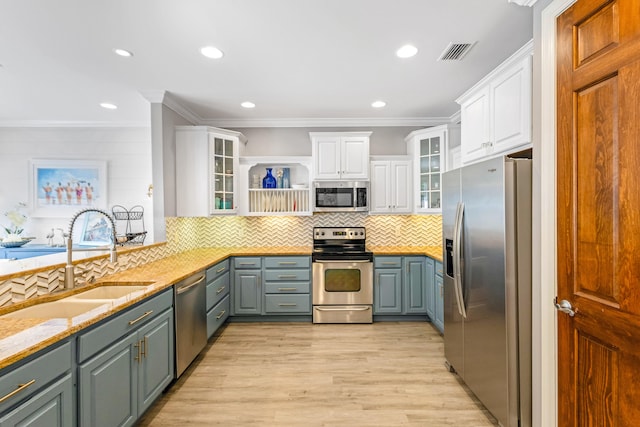 kitchen featuring white cabinetry, sink, stainless steel appliances, light stone countertops, and light wood-type flooring