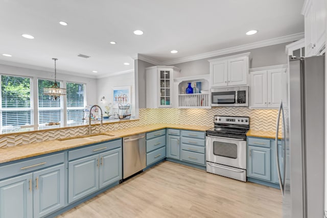 kitchen featuring appliances with stainless steel finishes, pendant lighting, sink, white cabinets, and light wood-type flooring