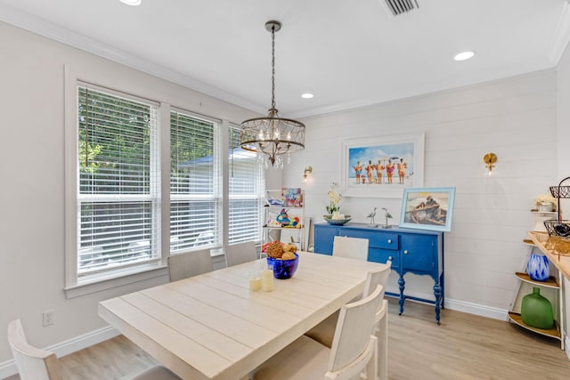 dining room with ornamental molding, a notable chandelier, and light wood-type flooring