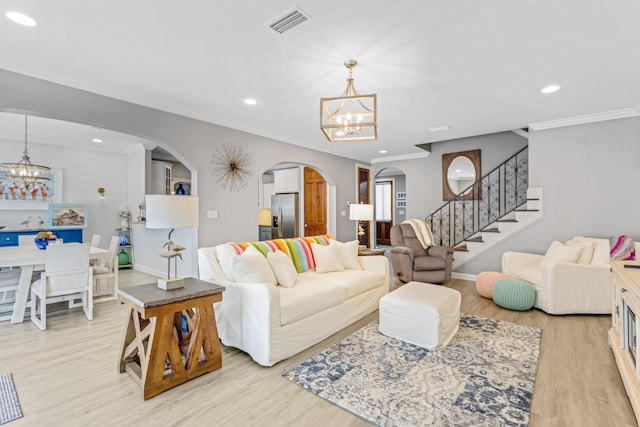 living room with crown molding, a chandelier, and light hardwood / wood-style flooring