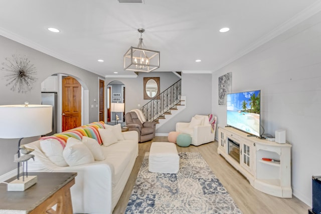 living room with a notable chandelier, light hardwood / wood-style floors, and ornamental molding