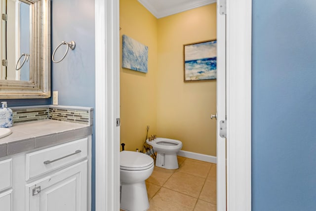 bathroom with tile patterned floors, toilet, a bidet, vanity, and decorative backsplash