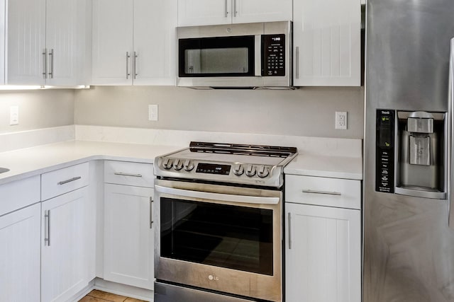 kitchen with light tile patterned floors, white cabinetry, and appliances with stainless steel finishes