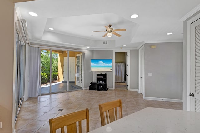 dining space with ceiling fan, a raised ceiling, light tile patterned floors, and crown molding