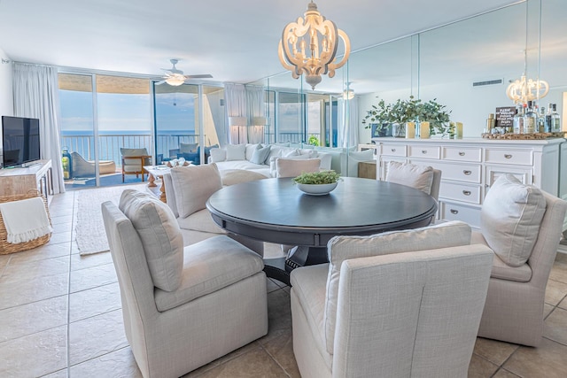 dining space with expansive windows, light tile patterned floors, a water view, and ceiling fan with notable chandelier