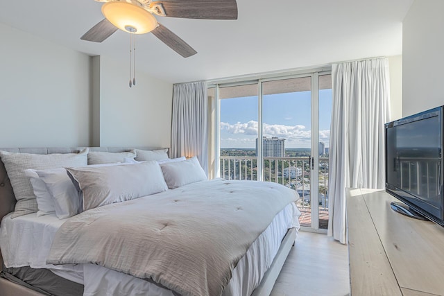 bedroom featuring access to exterior, ceiling fan, expansive windows, and light wood-type flooring