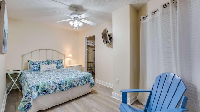 bedroom featuring ceiling fan, a textured ceiling, and light wood-type flooring