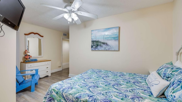 bedroom featuring ceiling fan, a textured ceiling, and light hardwood / wood-style floors