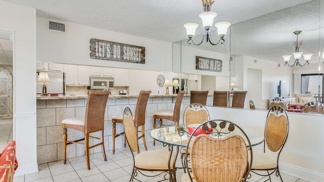 dining space with light tile patterned flooring, a textured ceiling, and a notable chandelier