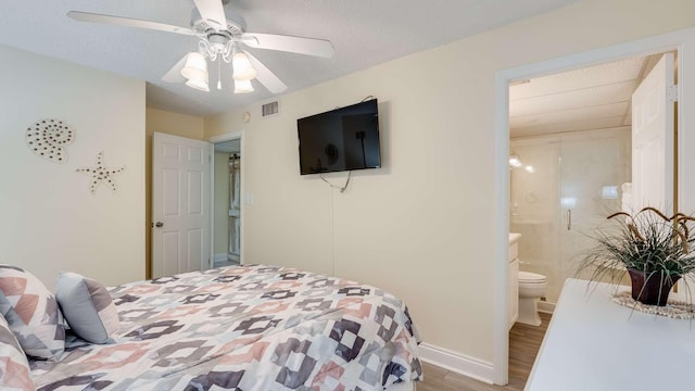 bedroom with ceiling fan, wood-type flooring, ensuite bathroom, and a textured ceiling