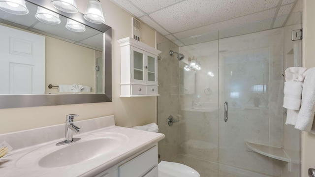 bathroom featuring vanity, toilet, a paneled ceiling, and a shower with shower door