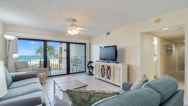 living room with a water view, light tile patterned floors, a textured ceiling, and ceiling fan