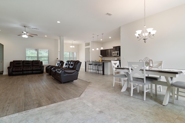 dining space featuring ceiling fan with notable chandelier