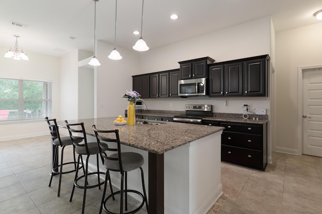 kitchen featuring a center island with sink, stainless steel appliances, stone counters, a breakfast bar, and decorative light fixtures