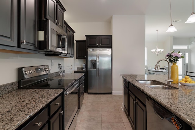 kitchen featuring light stone countertops, pendant lighting, a chandelier, appliances with stainless steel finishes, and sink