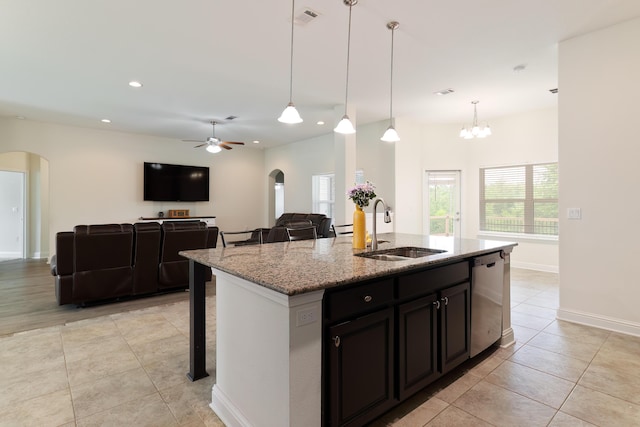 kitchen featuring a breakfast bar area, light stone counters, sink, stainless steel dishwasher, and ceiling fan with notable chandelier