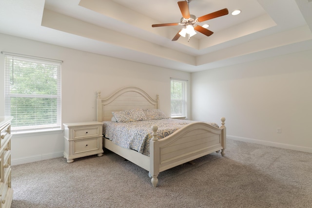 bedroom featuring ceiling fan, carpet floors, and a tray ceiling