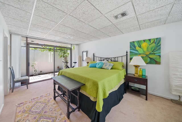 carpeted bedroom featuring a drop ceiling and a wall of windows