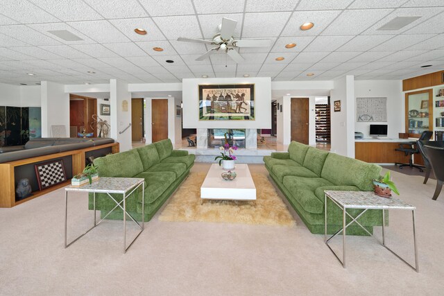 carpeted living room with a drop ceiling and ceiling fan