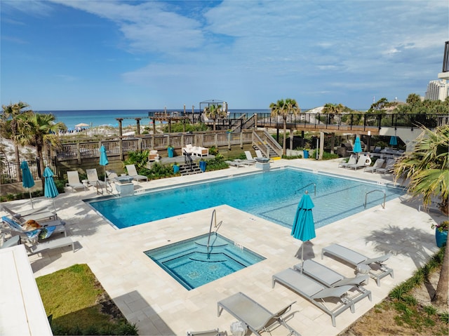 view of swimming pool with a community hot tub, a patio, and a water view