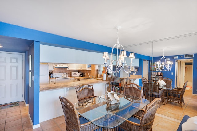 dining space featuring light tile patterned flooring, a notable chandelier, and sink