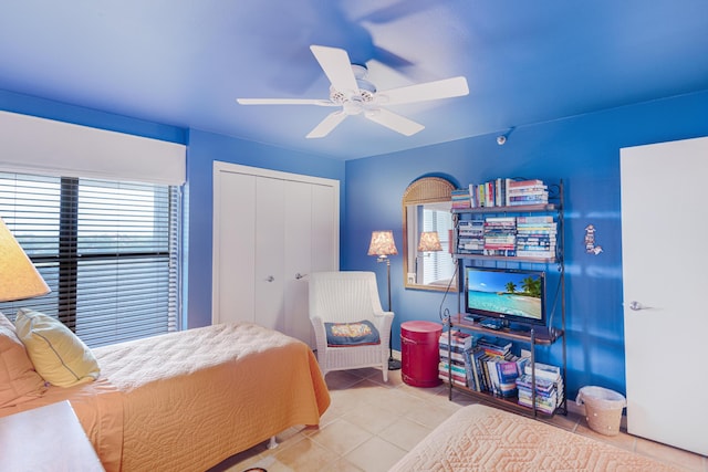 tiled bedroom featuring ceiling fan and a closet