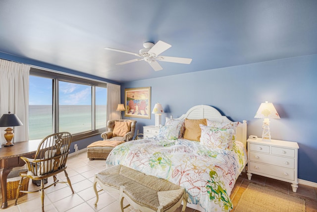 bedroom featuring ceiling fan, light tile patterned flooring, and a water view