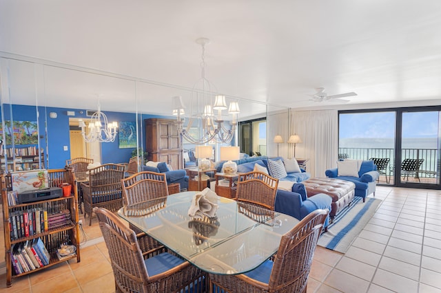 dining room featuring ceiling fan with notable chandelier, expansive windows, a water view, and light tile patterned floors