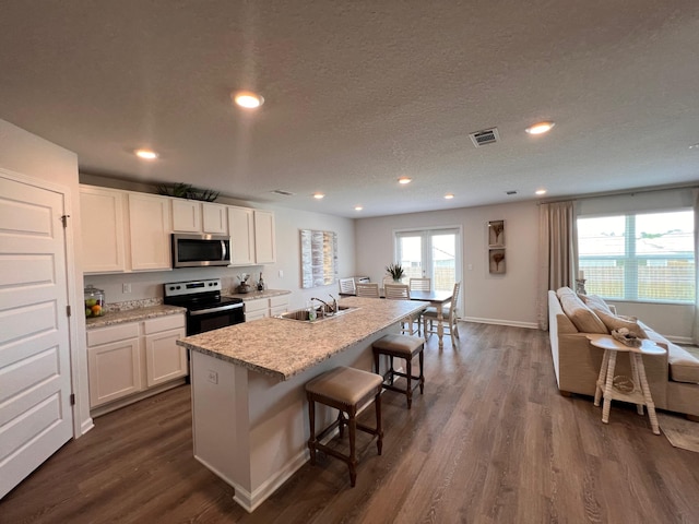 kitchen featuring dark wood-type flooring, white cabinets, sink, an island with sink, and appliances with stainless steel finishes