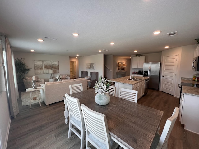 dining space with sink, dark wood-type flooring, and a textured ceiling