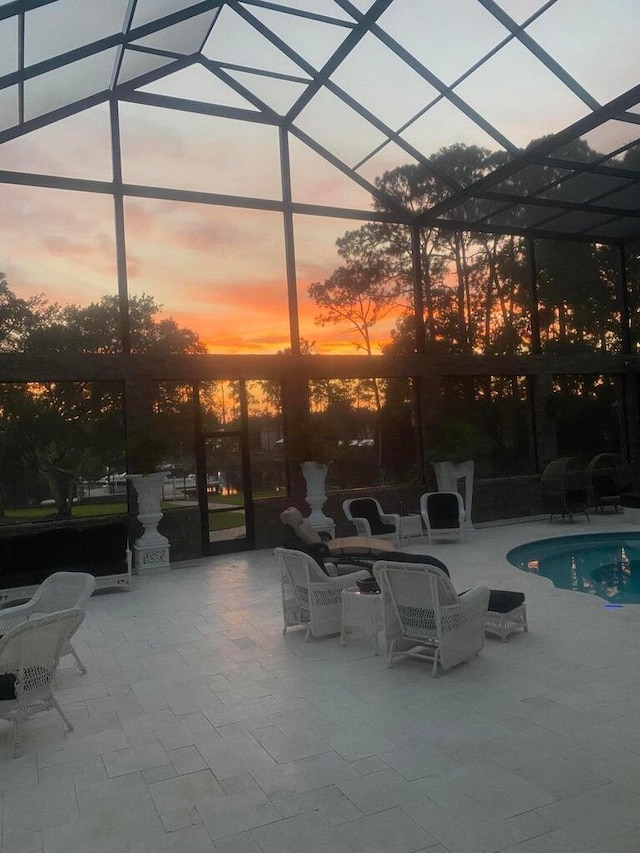 patio terrace at dusk with glass enclosure and an outdoor pool