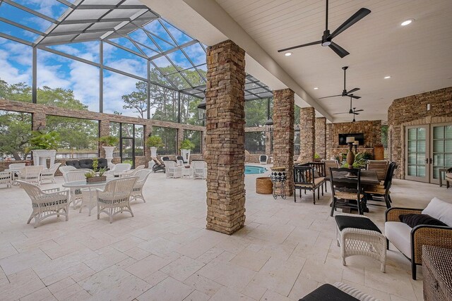 view of patio with a ceiling fan, french doors, glass enclosure, and a fireplace